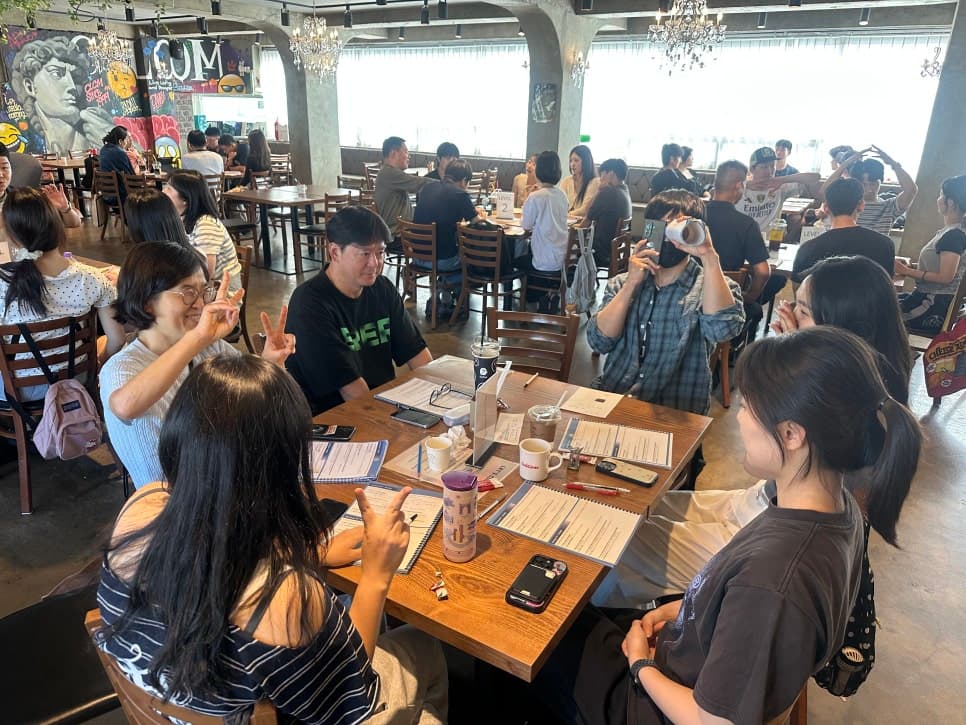 여러 테이블에서 자료를 보며 대화하는 참여자들