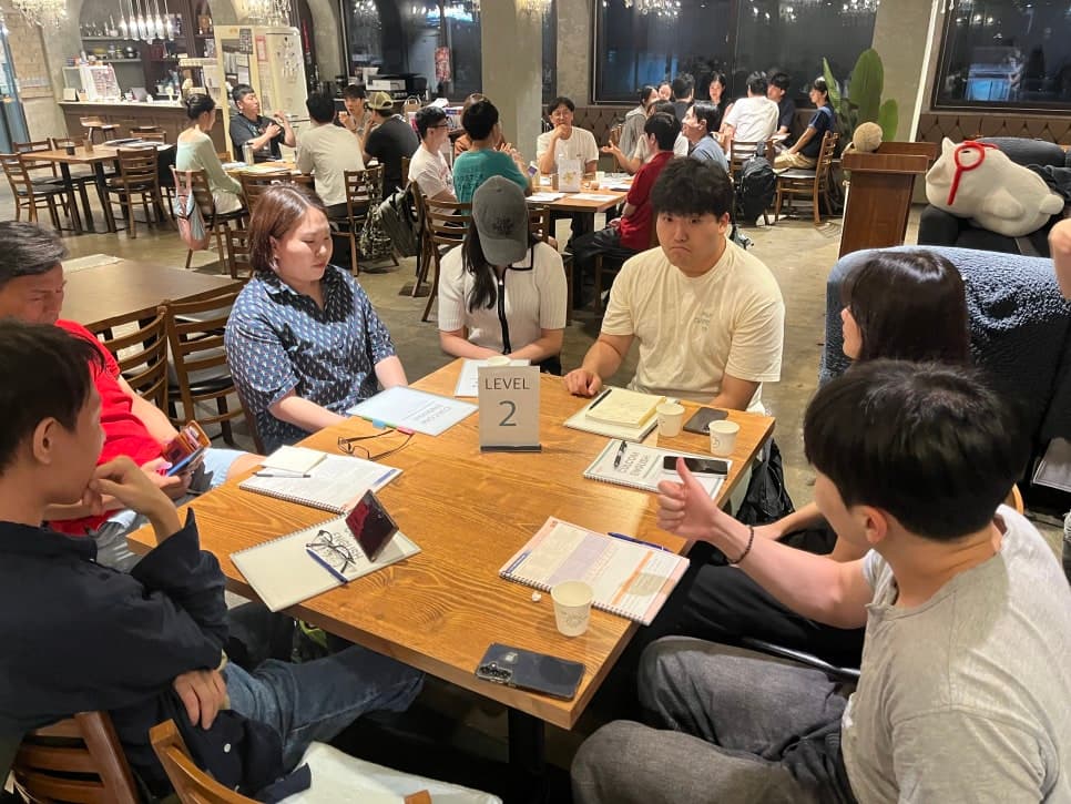 테이블에 둘러앉아 학습 자료를 보는 참여자들