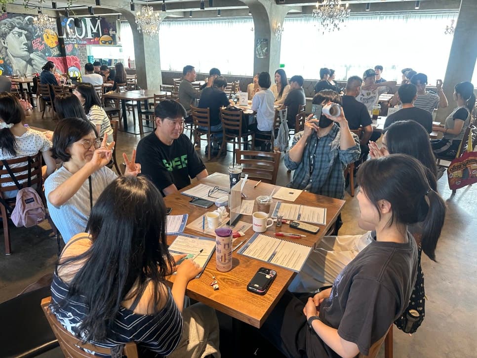 자료와 음료가 놓인 테이블에서 대화하는 참여자들