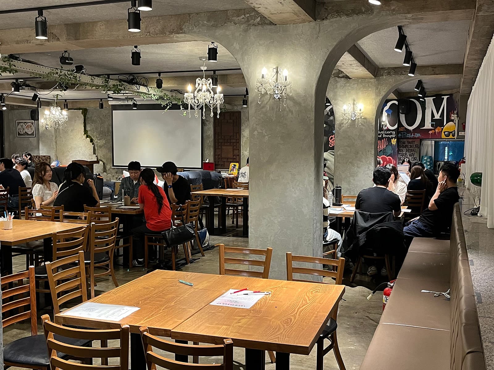 벽면 장식과 테이블 주변에 사람들이 앉아 있는 공간