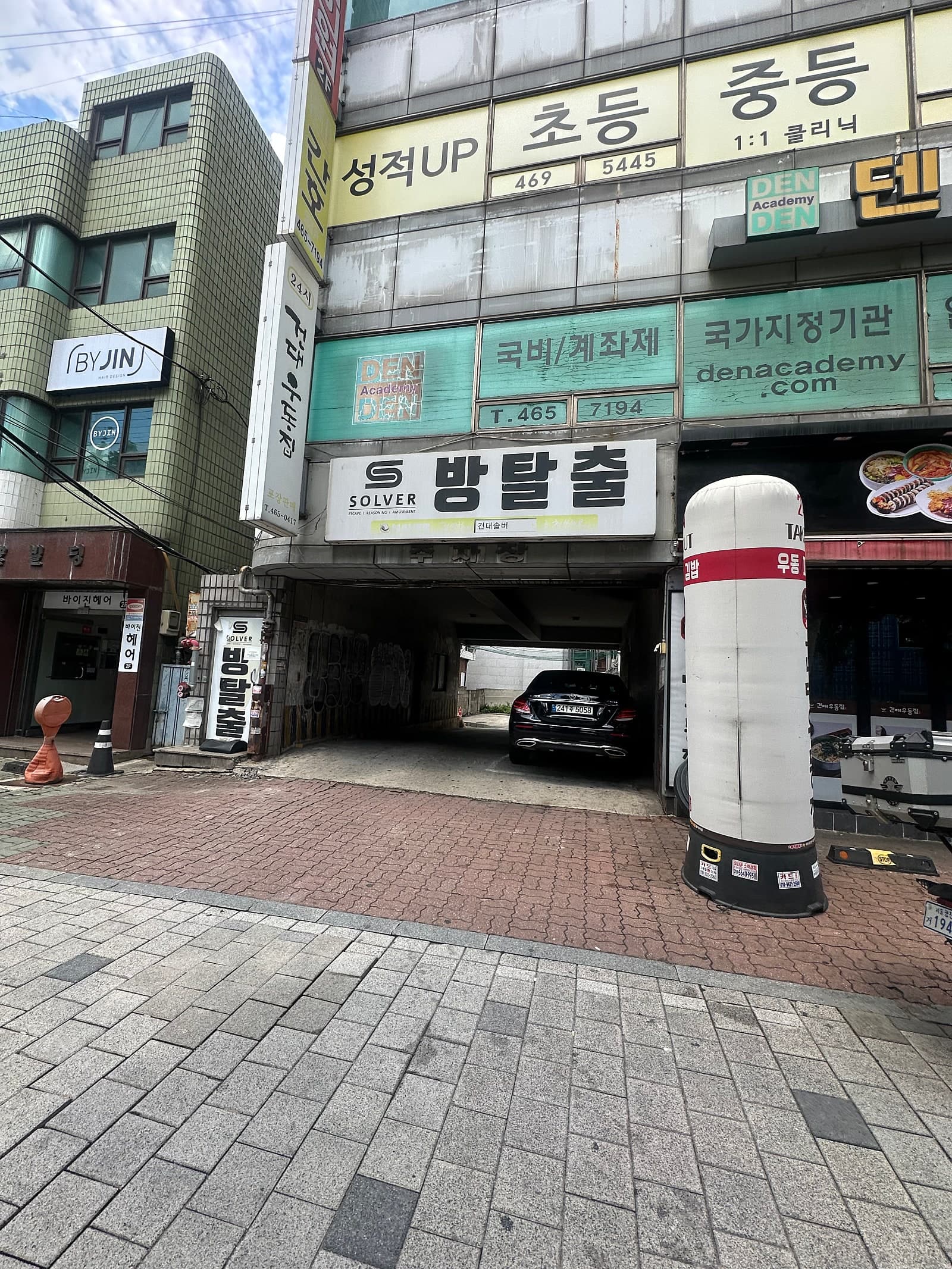 주변 상가와 차량 출입 공간이 보이는 건물 외관