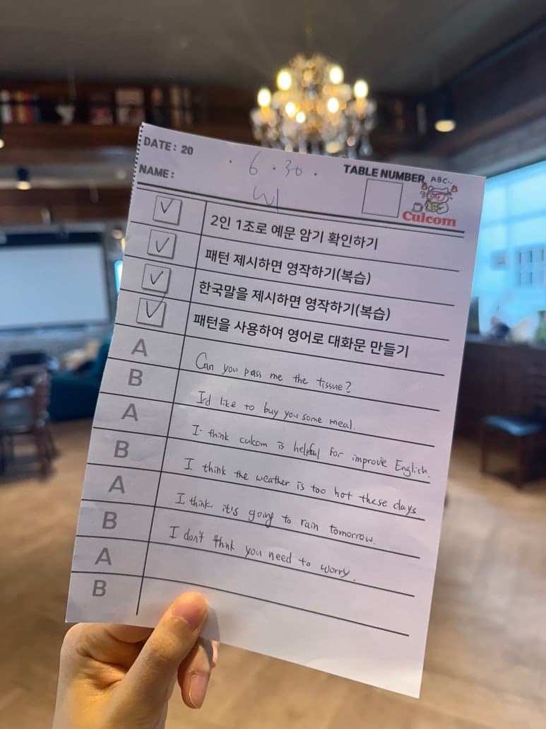 영어 문장과 질문이 적힌 학습 자료를 들고 있는 모습