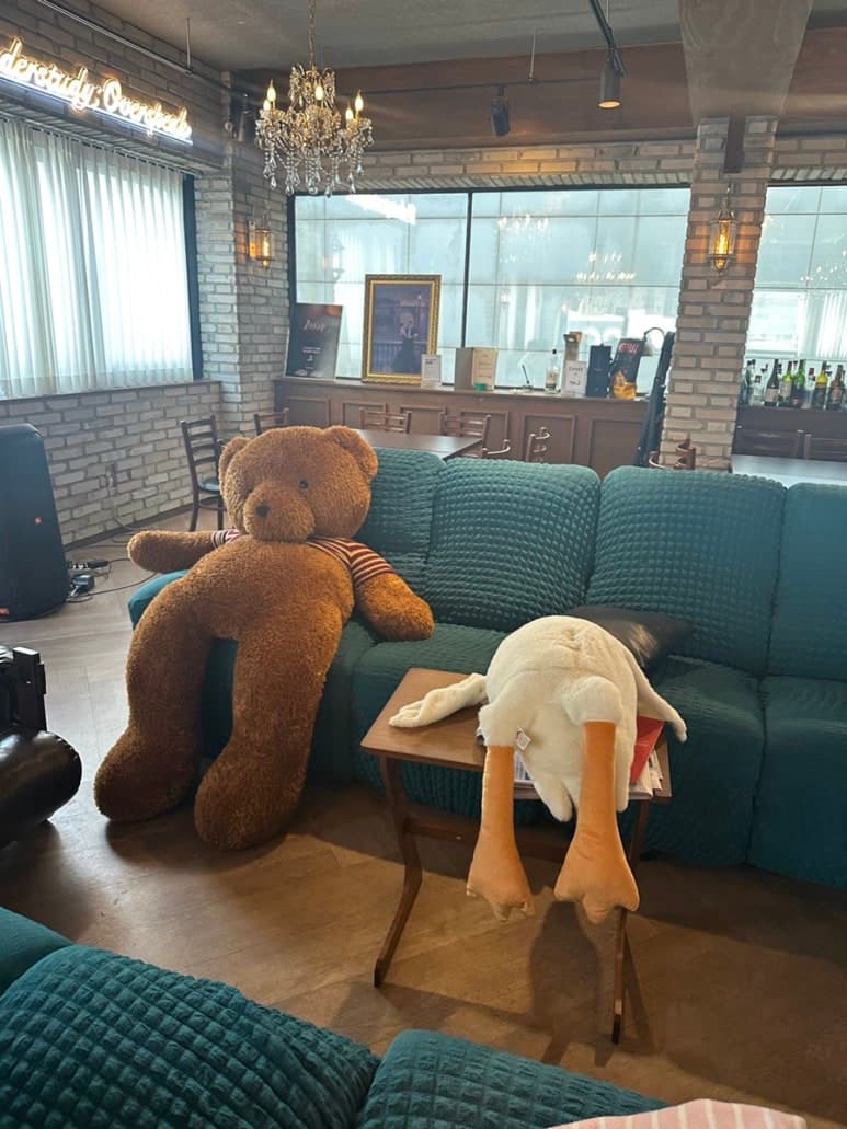 큰 인형과 초록색 소파가 놓인 창가 공간