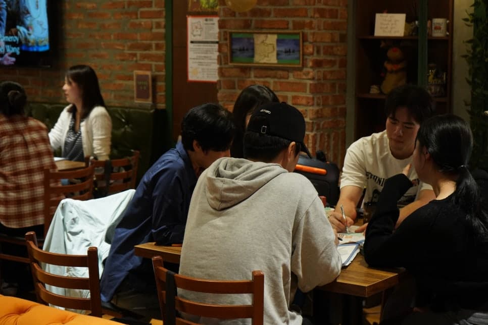 실내 테이블에 모여 자료를 살펴보는 참여자들