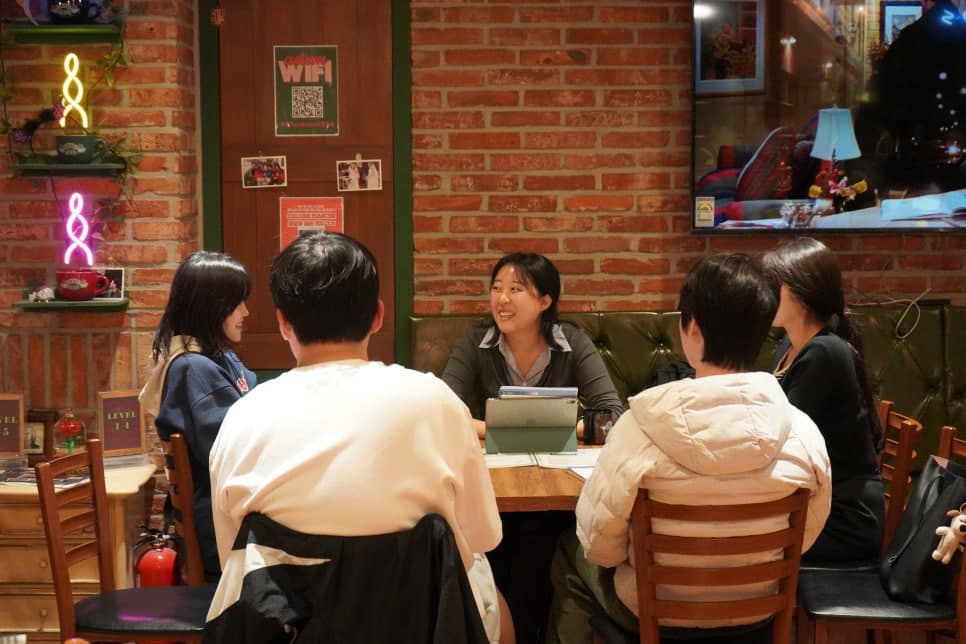 벽돌 벽면 옆 테이블에서 자료를 살펴보는 참여자들