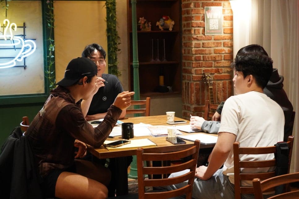 자료를 펼친 테이블에서 마주 앉아 대화하는 모습