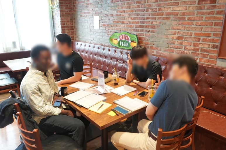창가와 벽돌 벽면 옆 테이블에서 대화하는 모습